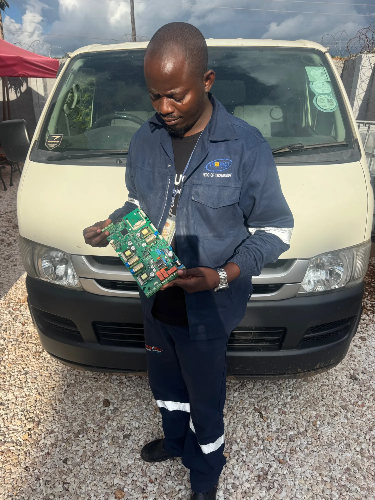 HCS technician with a repaired board beside the service van