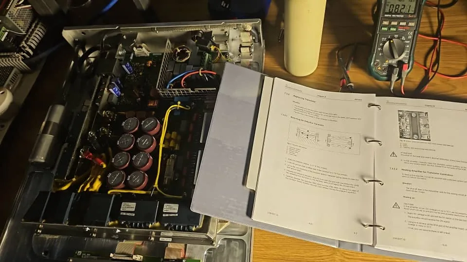Amplifier opened on the bench, service manual and multimeter at hand